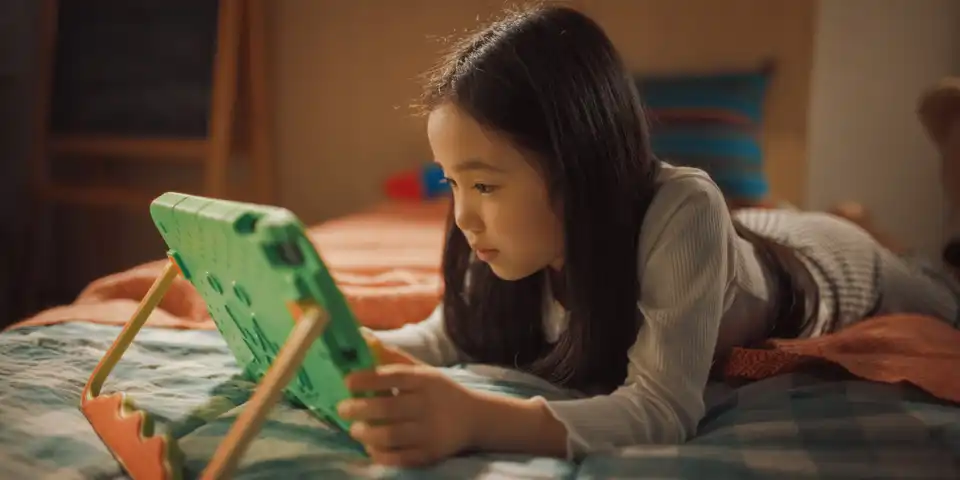 Girl Playing Learning Puzzle Video Game on a Tablet Computer at Home in Her Children's Bedroom