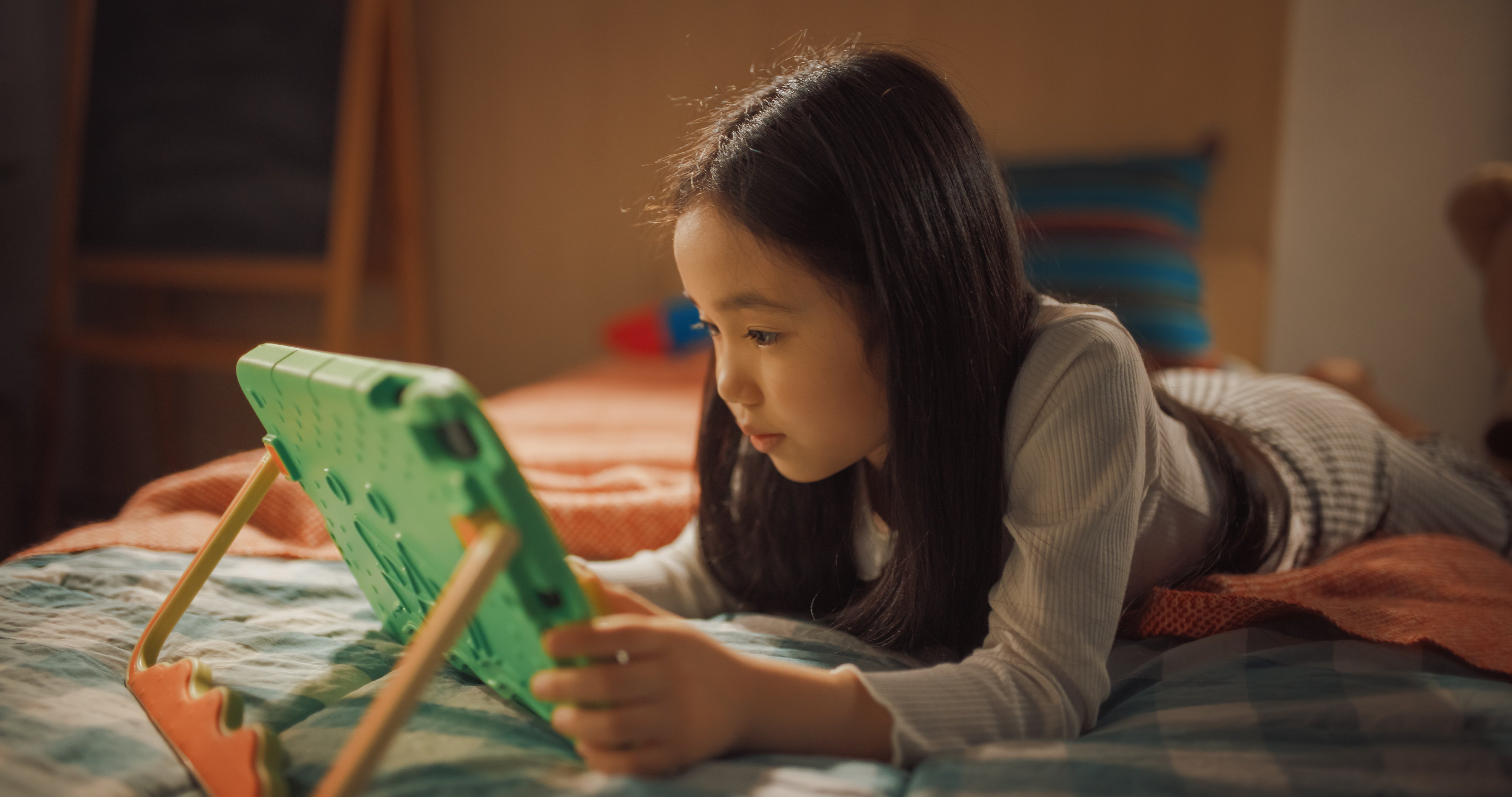 Girl Playing Learning Puzzle Video Game on a Tablet Computer at Home in Her Children's Bedroom