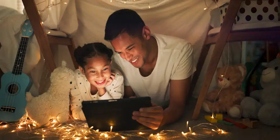 Tent, father and girl on tablet at night watching movies, online games and bedtime story with fairy lights